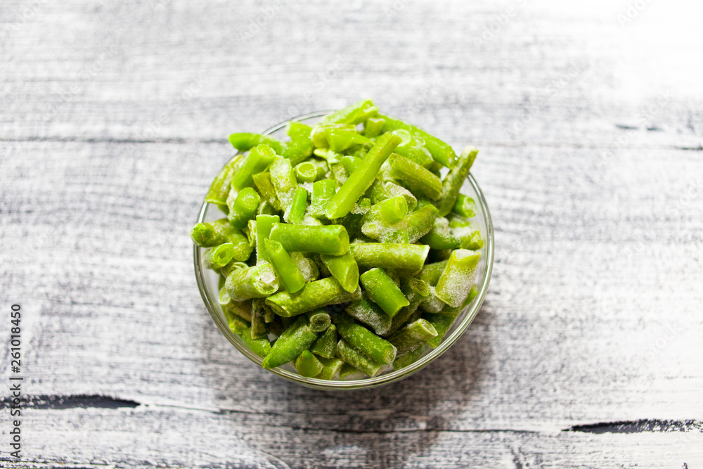Frozen beans. Glass bowl with frozen green beans on beautiful wooden background Frozen beans. Glass bowl with frozen green beans on beautiful wooden background