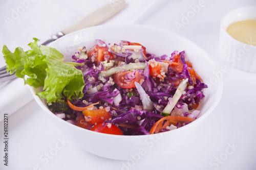 Spring salad with red cabbage, radishes, tomatoes, onion on the white bowl