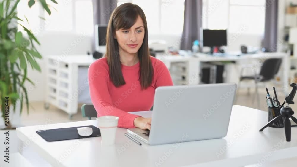 Young beautiful Caucasian businesswoman with brown hair sitting in office and using laptop. Young beautiful Caucasian businesswoman with brown hair sitting in office and using laptop.