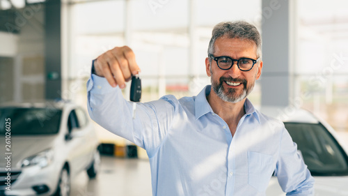 happy customer holding car keys in car showroom