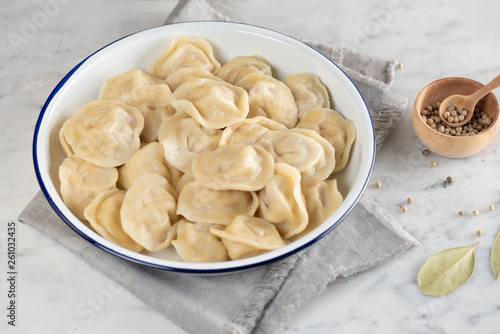 Homemade traditional Russian dumplings on a plate. Marble background, top view