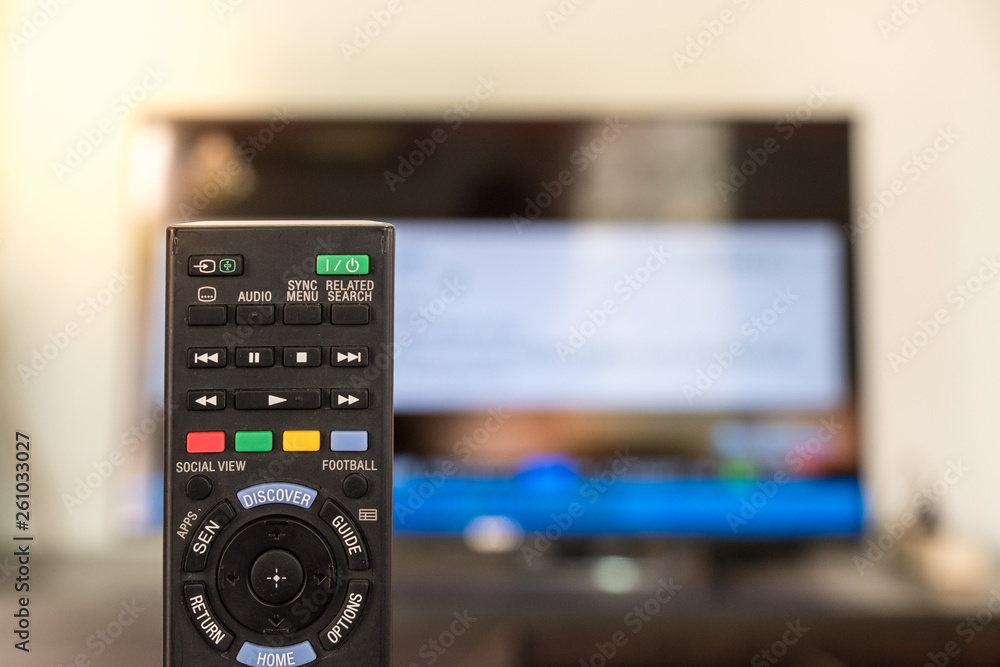 Black remote control. TV is blurred background Black remote control. TV is blurred background