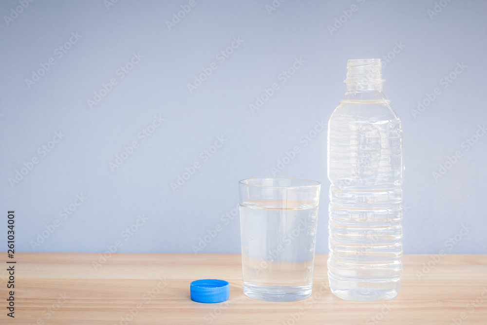 Refreshing natural mineral water in plastic bottle with transparent glass on wooden desk with copyspace Refreshing natural mineral water in plastic bottle with transparent glass on wooden desk with copyspace