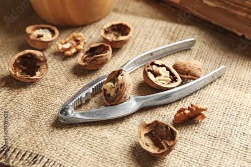 Nutcracker with tasty walnuts on table