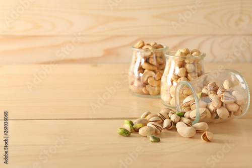 Jars with different tasty nuts on wooden table