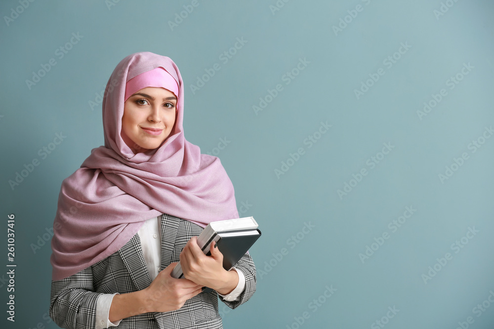 Young Muslim woman with books on color background Young Muslim woman with books on color background