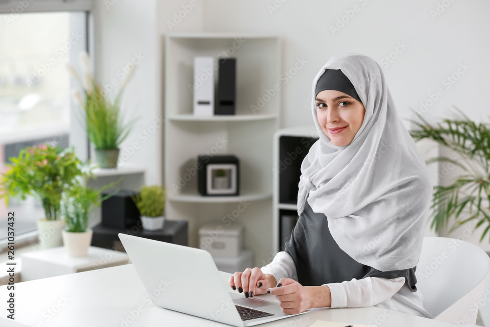 Muslim woman working on laptop in office Muslim woman working on laptop in office