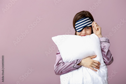 Fototapeta Sleepy woman with mask and pillow on color background