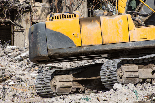 Close up details of excavator tracks on on the ruins of a house.