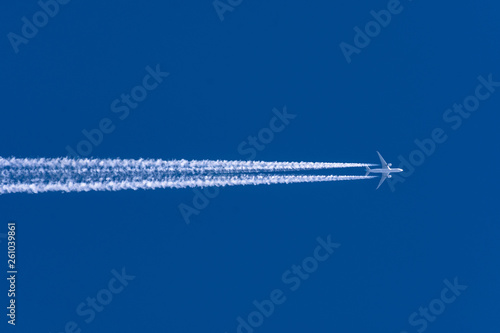 Airplanes leaving contrail trace from left to right on a clear blue sky. © aapsky