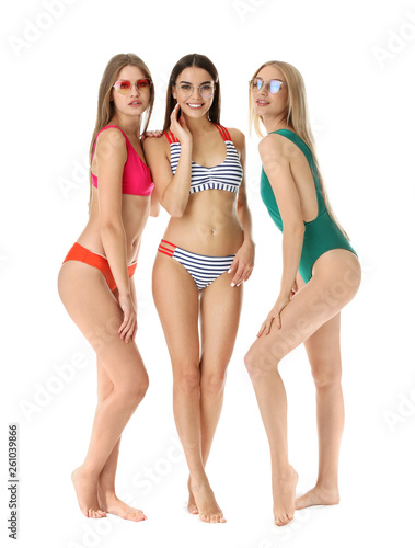 Beautiful young women in swimming suits on white background