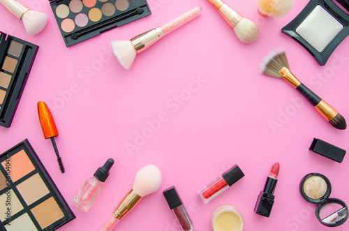 Cosmetics top view on a pink table. Workplace flat lay with cosmetics, lipstick and eyeshadow