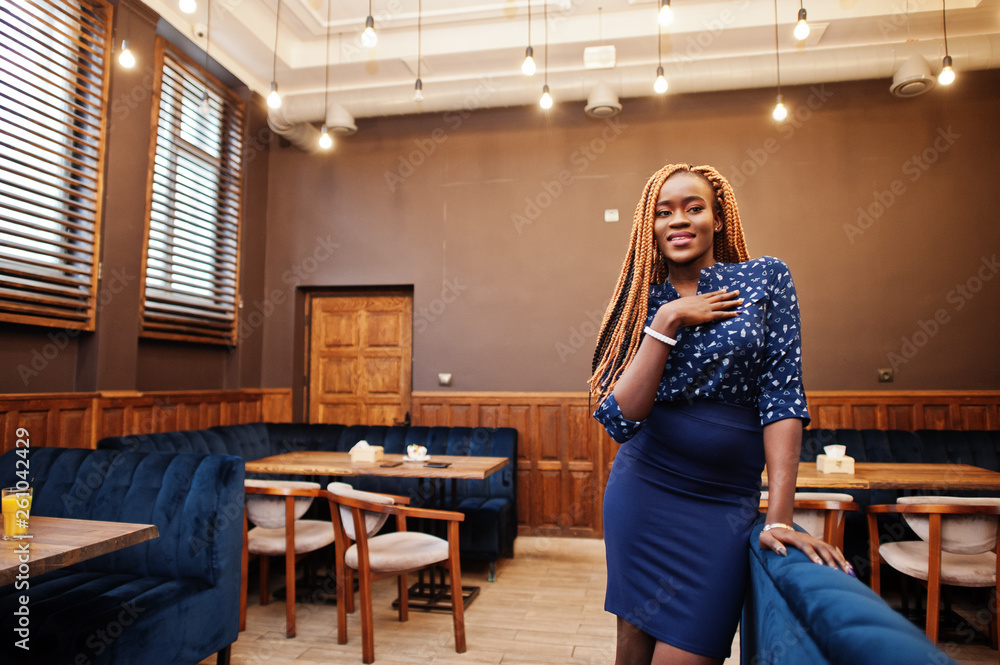 Portrait of beautiful young african business woman with dreadlocks, wear on blue blouse and skirt, posed in cafe. Portrait of beautiful young african business woman with dreadlocks, wear on blue blouse and skirt, posed in cafe.