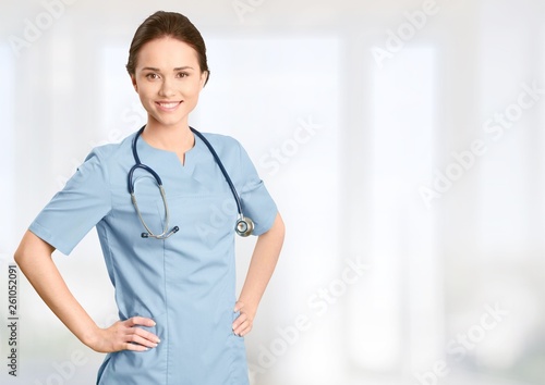 Young female doctor with stethoscope on blurred hospital background