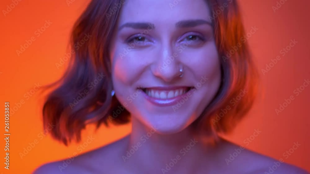 Closeup shoot of young attractive caucasian female looking at camera laughing with joy with neon red background Closeup shoot of young attractive caucasian female looking at camera laughing with joy with neon red background