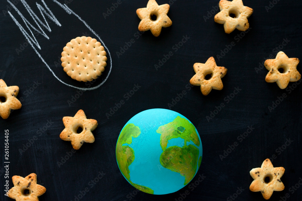 top view handmade model of Earth planet, cookie meteorite and cookies in the shape of stars on the chalkboard , space and astronomy concept top view handmade model of Earth planet, cookie meteorite and cookies in the shape of stars on the chalkboard , space and astronomy concept