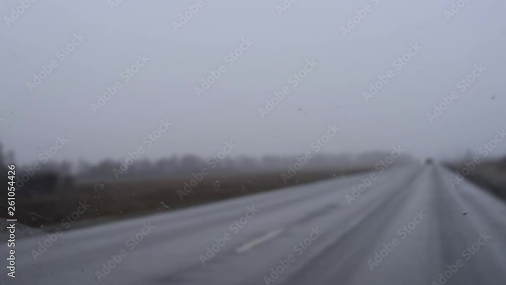 The windshield of the car with drops of water and dirt in cloudy weather, snow and rain is cleaned with wipers . In early spring or late autumn, the gray sky is overcast. The windshield of the car with drops of water and dirt in cloudy weather, snow and rain is cleaned with wipers . In early spring or late autumn, the gray sky is overcast.