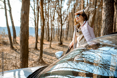 Young woman traveler enjoying nature while traveling by car in the picturesquare forest with lake