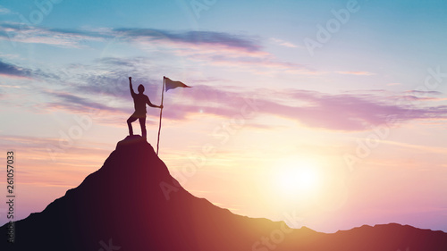 Fotografie, Obraz Man with flag celebrates victory on top of a mountain at sunset