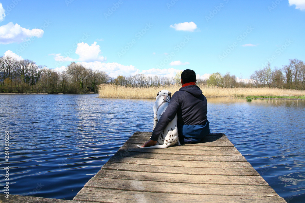 un homme et son chien assis sur un ponton un homme et son chien assis sur un ponton