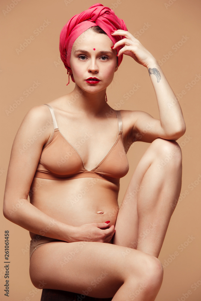Young beautiful pregnant woman posing on brown background. Happy caucasian female model sitting at studio. Pregnancy, parent, maternity, mothers day, parenthood and family concept. Young beautiful pregnant woman posing on brown background. Happy caucasian female model sitting at studio. Pregnancy, parent, maternity, mothers day, parenthood and family concept.
