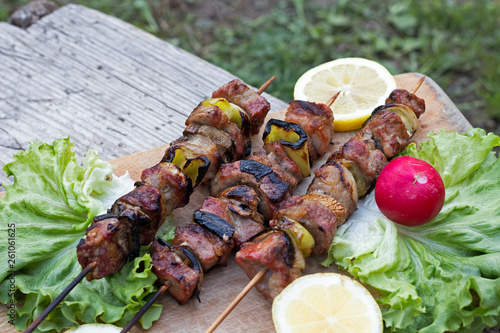Grilled Pork Kebab with lettuce leaves, radish and lemon over wooden background, Eastern cuisine