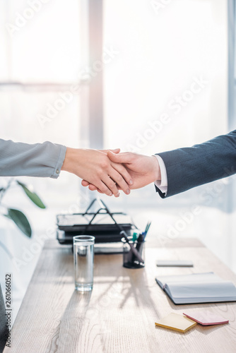 cropped view of recruiter and employee shaking hands in modern office