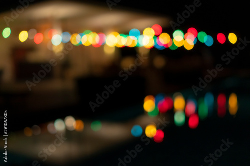 Colourful of bokeh/blur light at pool bar located by outdoor swimming pool at night time 
