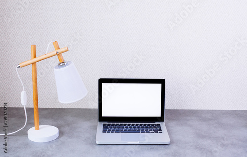 Front view of desktop with blank laptop on wall background