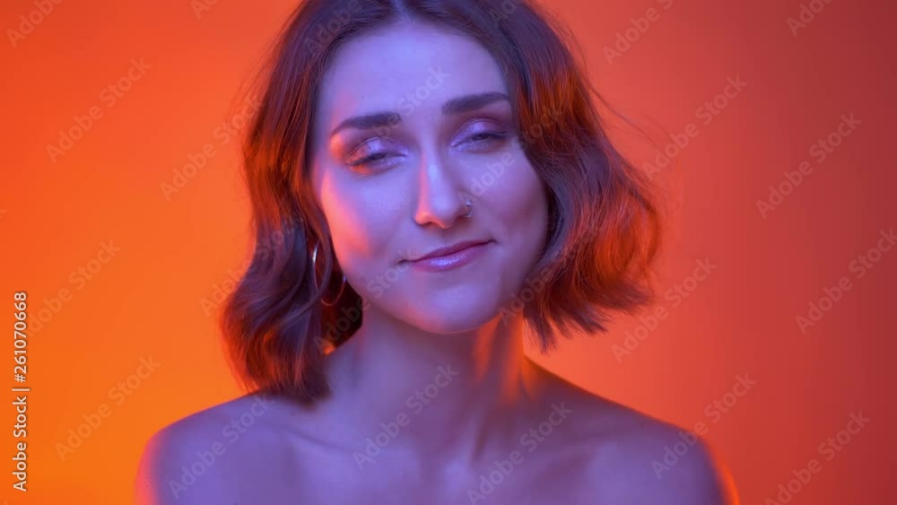 Closeup shoot of young carefree attractive caucasian female laughing happily looking at camera with neon red background Closeup shoot of young carefree attractive caucasian female laughing happily looking at camera with neon red background