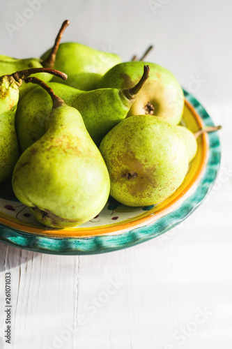 Fresh pears on a plate on white wooden table