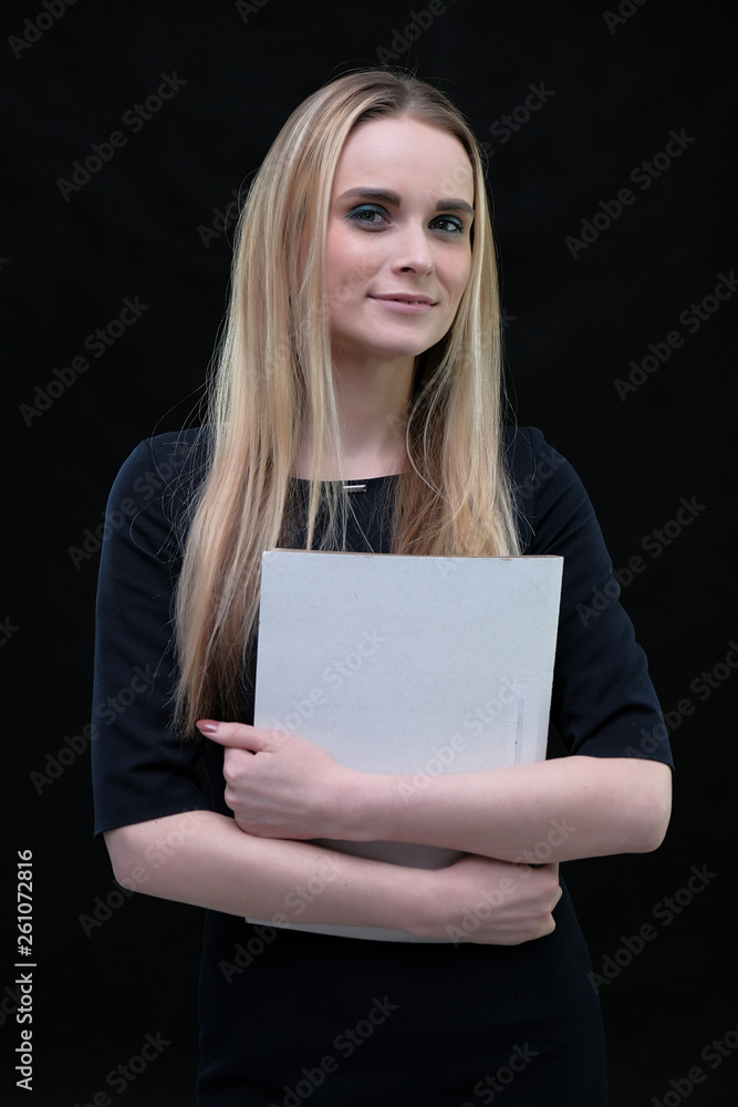 Studio portrait concept of a beautiful fashionable blonde business girl standing and talking in a business dress on a black background with a folder in hands. Studio portrait concept of a beautiful fashionable blonde business girl standing and talking in a business dress on a black background with a folder in hands.