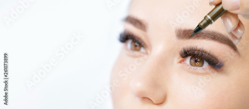 Billede på lærred Beautiful young girl with long eyelashes tweezing her eyebrows in a beauty salon
