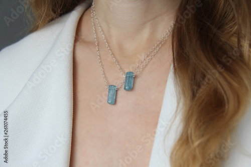 Crystal blue aquamarine beryl on a silver chain on the girl. Pendant aquamarine, pendant, decoration on the neck. Natural blue aquamarine. Minimalism, Zen. Copy space for your text
