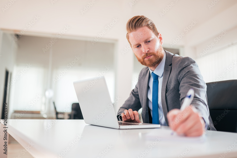 Serious businessman in formalwear taking notes at work, low angle image. Serious businessman in formalwear taking notes at work, low angle image.