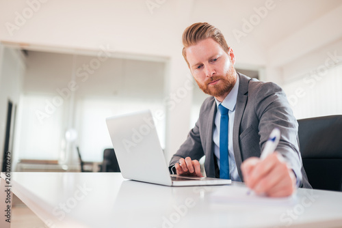 Serious businessman in formalwear taking notes at work, low angle image. © bnenin