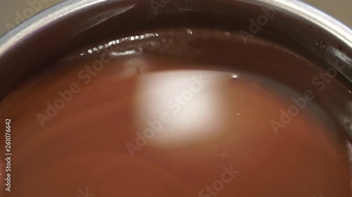 A Silver Ladle is Dipped into Liquid Chocolate to Stir photo