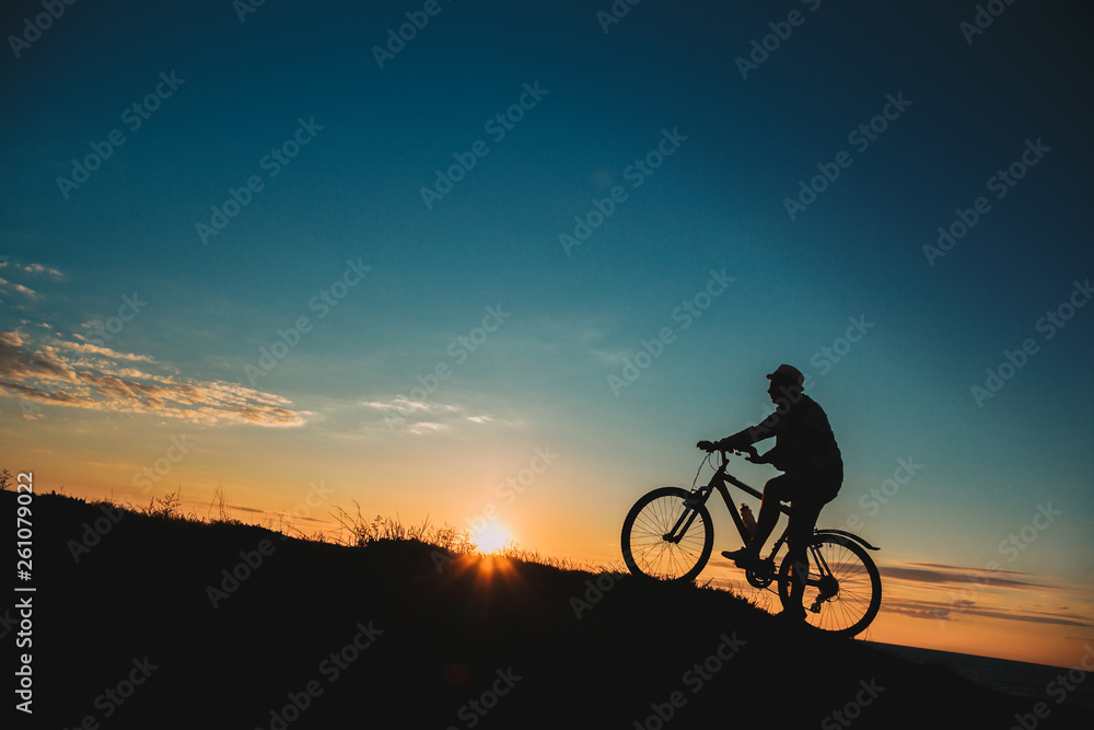 Obraz premium Silhouette of a male mountainbiker at sunset in the mountains