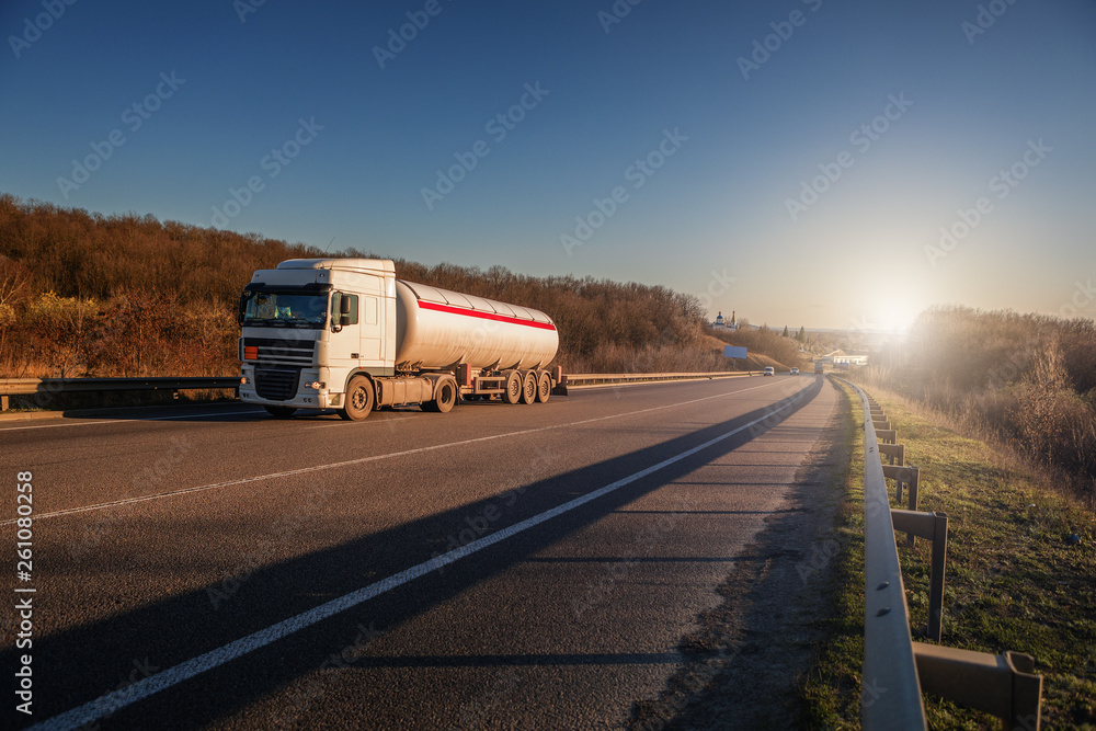 Arriving white truck on the road in a rural landscape at sunset