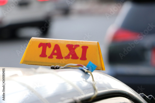 Taxi light sign or cab sign in yellow color with red text on the car roof at the street blurred background.