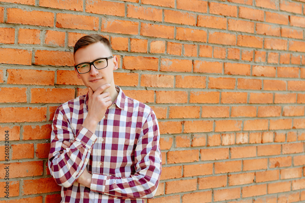 Portrait of a guy in a shirt and glasses against a brick wall Portrait of a guy in a shirt and glasses against a brick wall