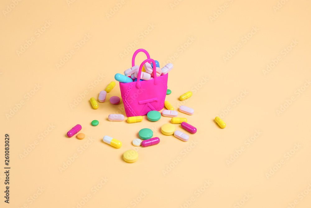 Colored pills fall out of a pink handbag on an orange background