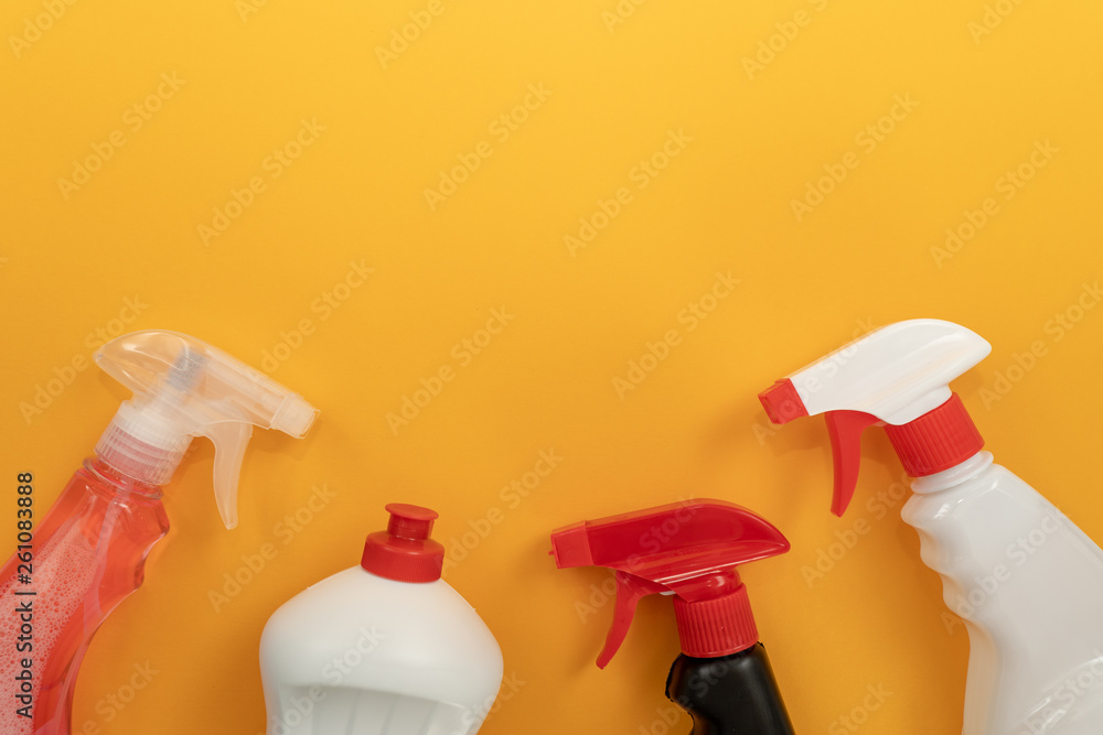Tops of white, black and transparent plastic bottles of different detergents on orange background. Spring house cleaning Tops of white, black and transparent plastic bottles of different detergents on orange background. Spring house cleaning