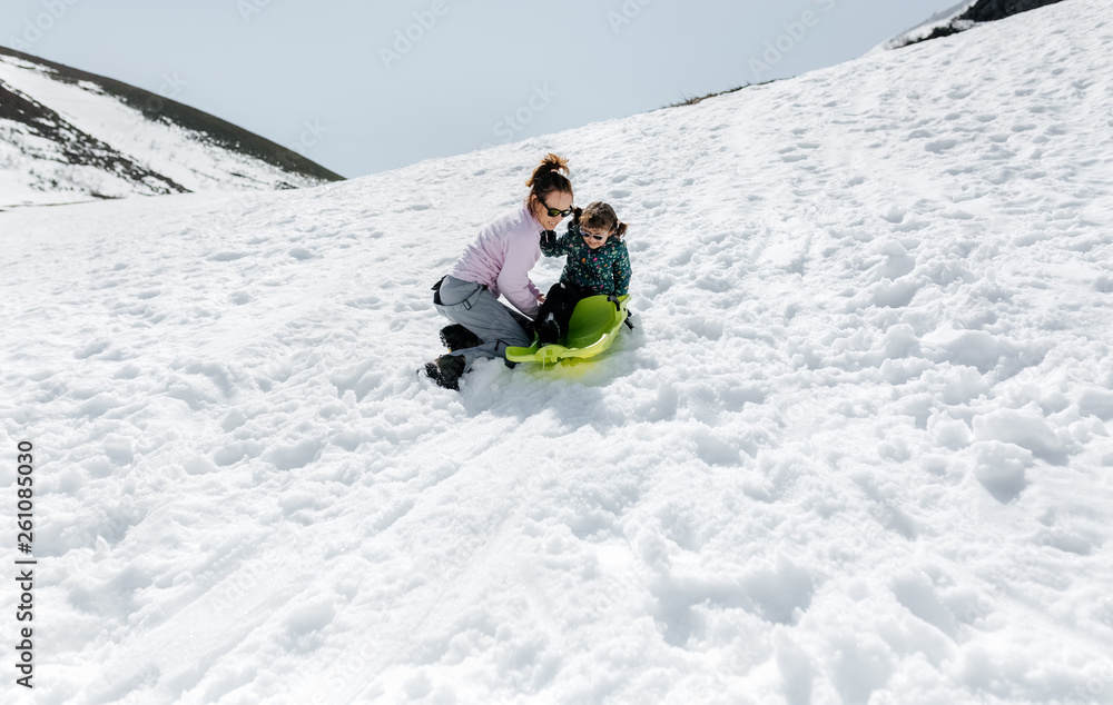 Mother with her daughter playing with a sled Mother with her daughter playing with a sled