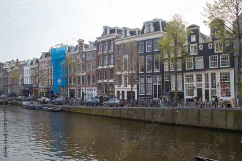 Amsterdam/Netherlands, April 06, 2019: Old streets along numerous canals in Amsterdam. River transport and bicycles © Olena