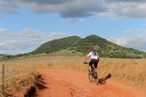 Ciclista praticando o esporte mountainbike em trilha de terra vermelha