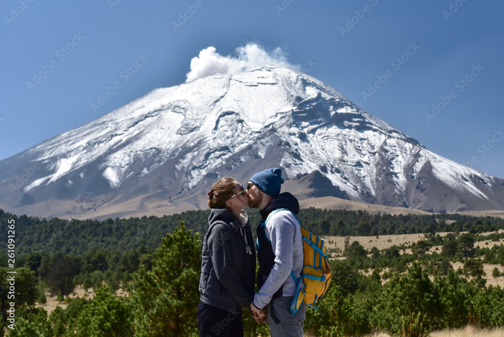 Young couple kissing in front of active volcano Young couple kissing in front of active volcano