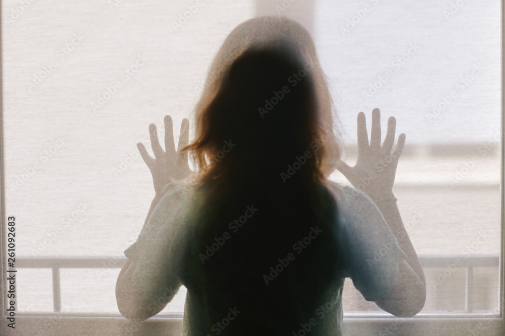 © Miquel Llonch/Stocksy - Rear view of girl looking through window