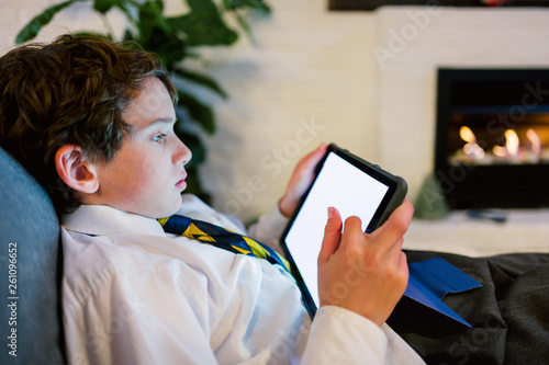 Boy transfixed and lit by the screen of a tablet