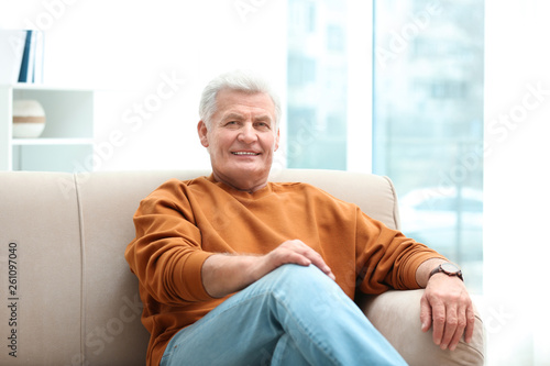 Portrait of handsome mature man on sofa indoors © New Africa
